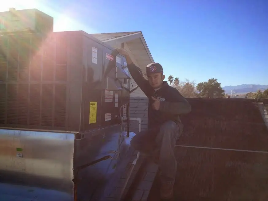 HVAC technician performing AC Tune-Up on a rooftop unit in North Elba
